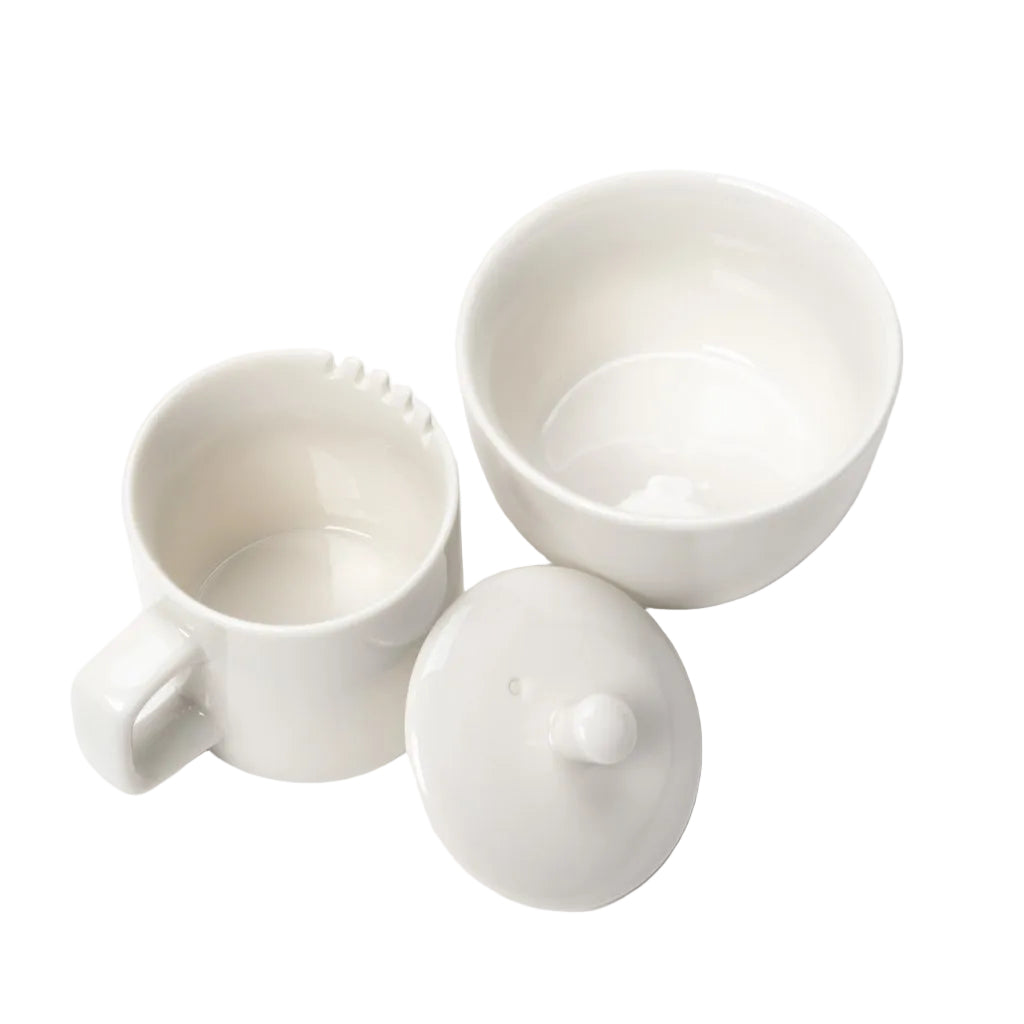 Set of white ceramic containers including a mug, bowl, and lid on a light gray background