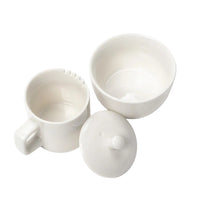 Set of white ceramic containers including a mug, bowl, and lid on a light gray background